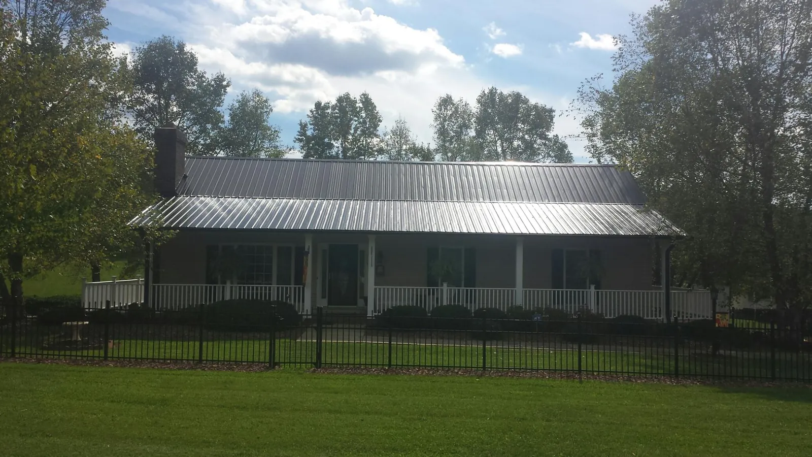 Gray metal roof on a brick ranch with a full width front porch — Gutter Guard Installation work by our crew in Ventura