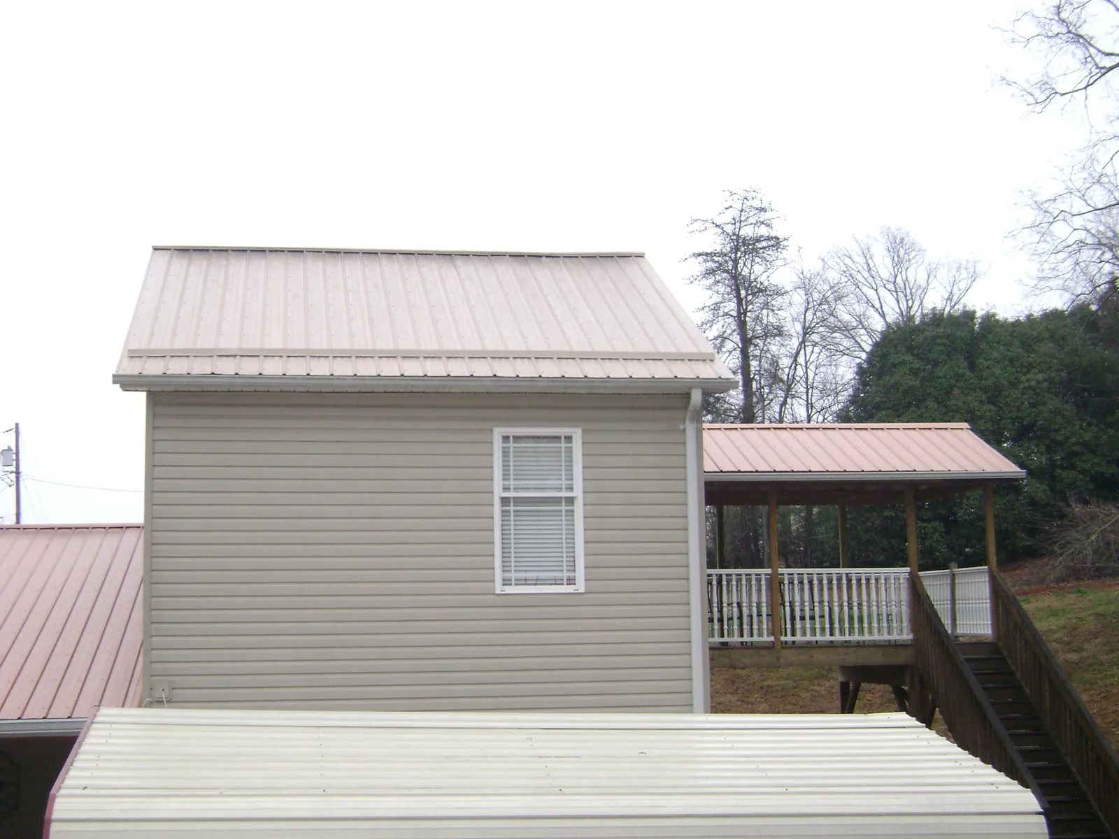 Tan metal roofs on a two story addition and attached porch, from a Roof Replacement job in Ventura